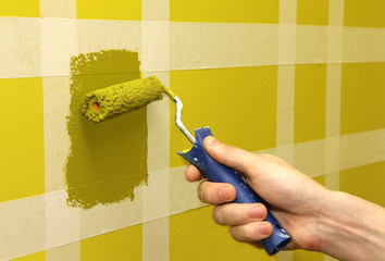Man painting wall with masking tape