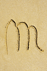 m letter written in the sand on a beach