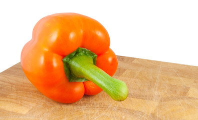 orange pepper on chopping block isolated on white