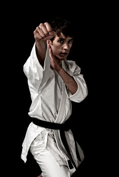 High Contrast karate young male fighter on black background.