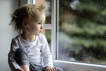 Adorable toddler girl looking at raindrops