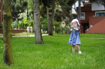 Adorable toddler girl playing with a grass