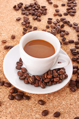 Small white  cup of coffee with coffee grain   on brown backgrou
