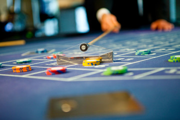 Coupier schiebt Jetons auf Roulettetisch