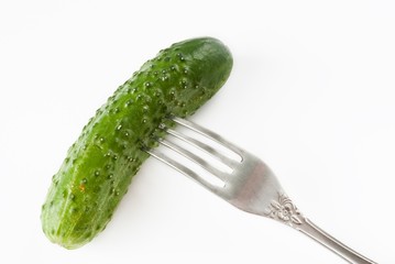 pickled gherkin on fork over white background