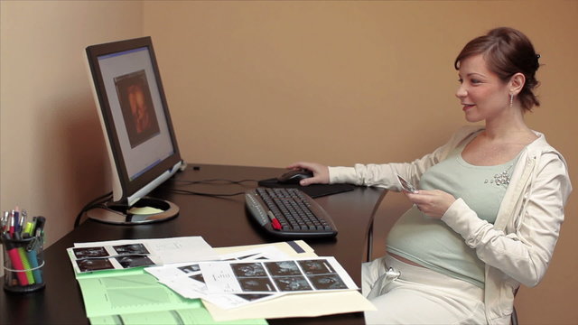6 months pregnant woman watching scans of her baby on pc