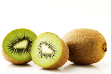 eine Kiwi und zwei Kiwihälften auf weißem Hintergrund