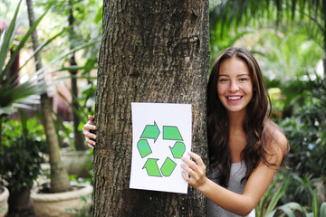 recycling: woman in the forest holding a recycle sign