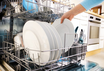 female hands loading dishes to the dishwasher