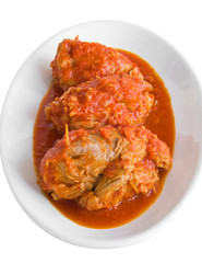 Meat roulade in tomato sauce on white dish.