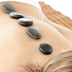 Relaxed woman lying on a massage table with stones