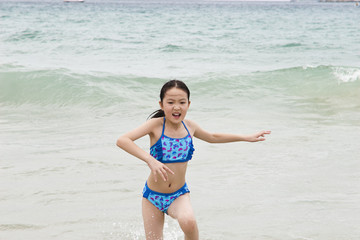 little asian girl running away from the tide
