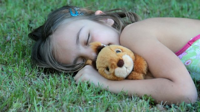 endormie dans l'herbe avec sa peluche