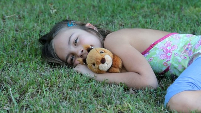 allong&eacute;e dans l'herbe avec la peluche &eacute;cureuil