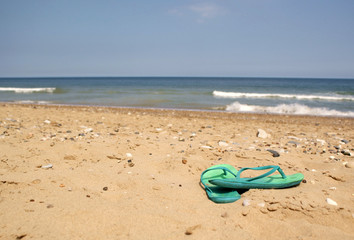 Fototapeta na wymiar Green Flip Flops on Beach