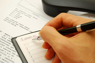 Writing with black pen on planner