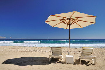 Parasol et transats sur la plage.