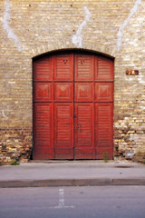 old red wooden gate in a brick wall