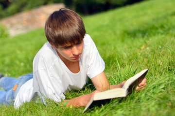 Naklejka na ściany i meble The teenager reads the book on a summer meadow