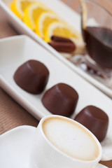 Coffee cup, chocolates plat and tea with lemmon
