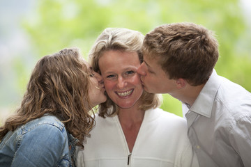 glückliche Mutter wird von Tochter und Sohn geküsst