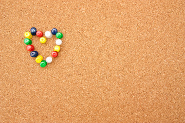 Many pushpins in a shape of a heart on corkboard
