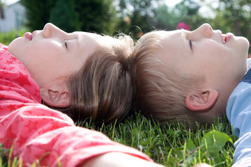 Chłopiec i dziewczynka leżą na trawie - obrazy, fototapety, plakaty