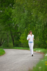 Jogging - sportive woman running on road in nature