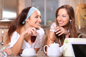 Happy women with wine in kitchen