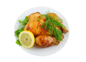 Grilled chicken with lemon and greens on plate isolated