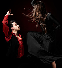 Young couple passion flamenco dancing on red light background. - obrazy, fototapety, plakaty
