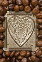 Antique heart chocolate tin mold surrounded with candy