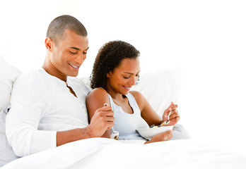 Obraz premium Smiling couple having breakfast lying on their bed