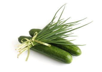 A bunch of green onions and cucumbers on a white background