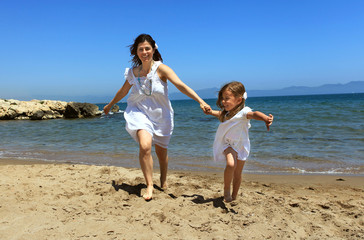 Mother and daughter running from the water's edge on a beach