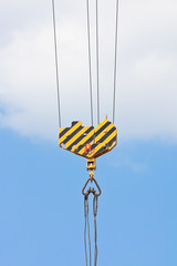 Crane hook over blue sky with clouds