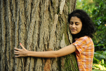 In love with nature: woman hugging a tree in the forest