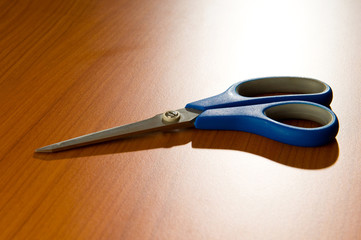 Office scissors against wooden background