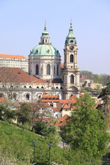 Fototapeta na wymiar Prague's St. Nicholas' Cathedral with flowering trees