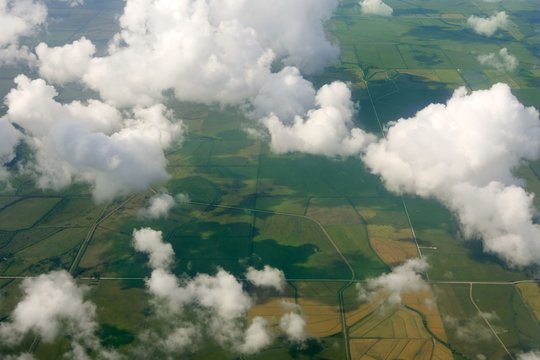 Aircraft bird view of green fields white clouds