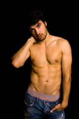 Fototapeta premium Young man with atletic body on black background