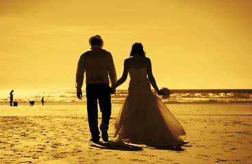 Silhouette image of a bride and groom by the beach at sunset.
