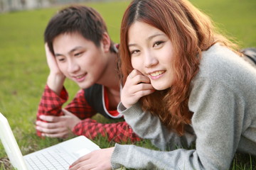 couple of asian using laptop on grass