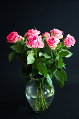Pink roses in a glass vase on black