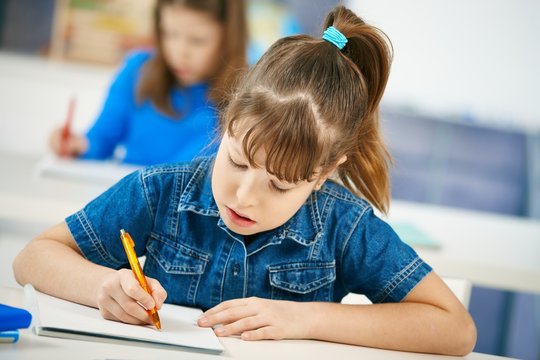 Young girl writing at school