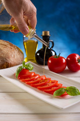 putting olive oil over tomatoes salad