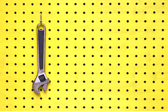 One adjustable wrench hangs from a hook on yellow pegboard