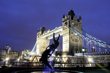 girl with a dolphin sculpture in front of Tower Bridge