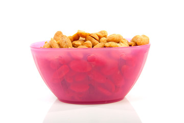pink bowl with salted peanuts over white background