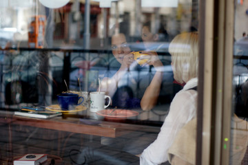 Fototapeta na wymiar Girls in cafe. The photo through glass